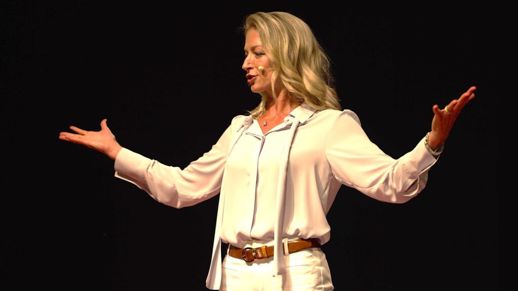 Elia Nichols on stage with arms spread wide